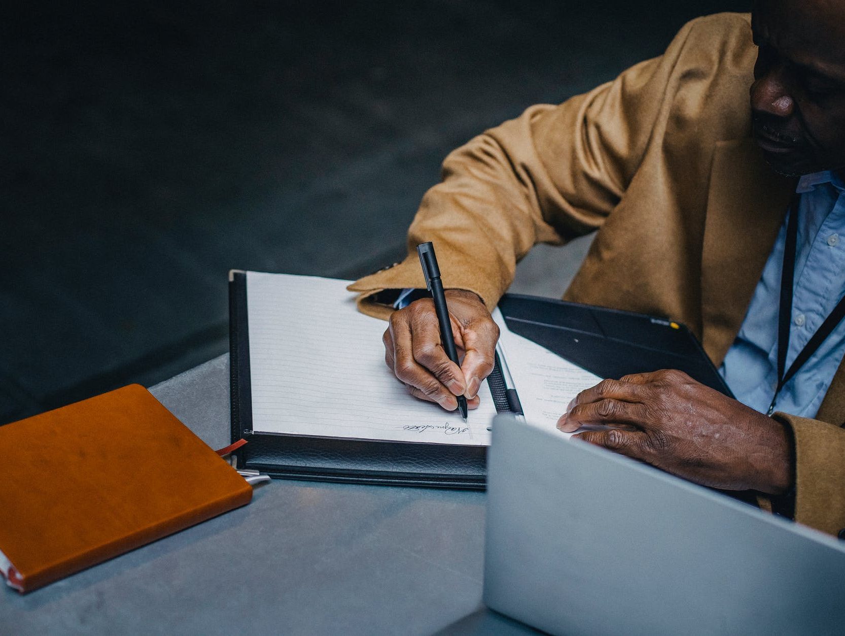 crop ethnic businessman taking note on paper sheet at table