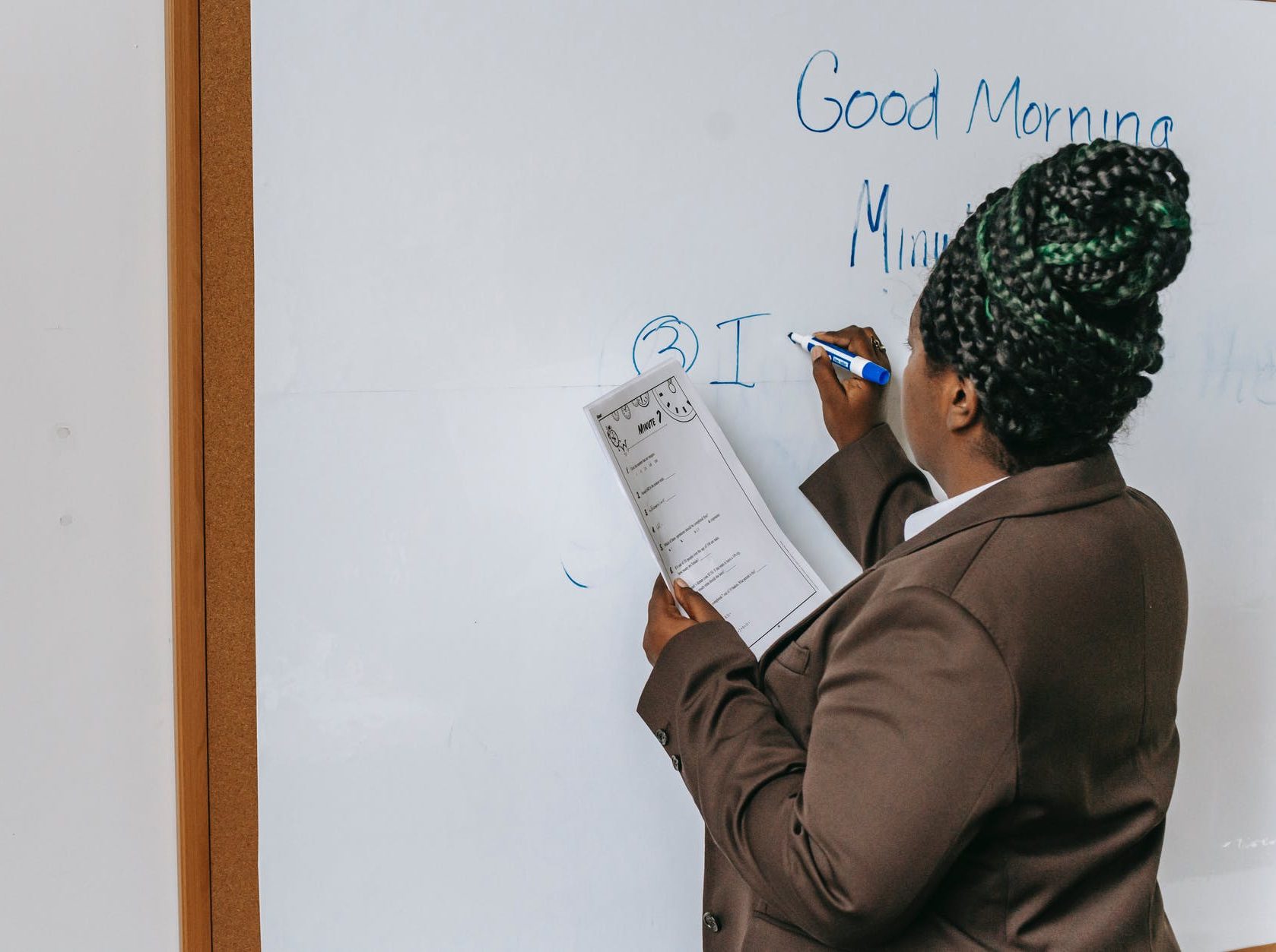 faceless black female teacher writing on whiteboard
